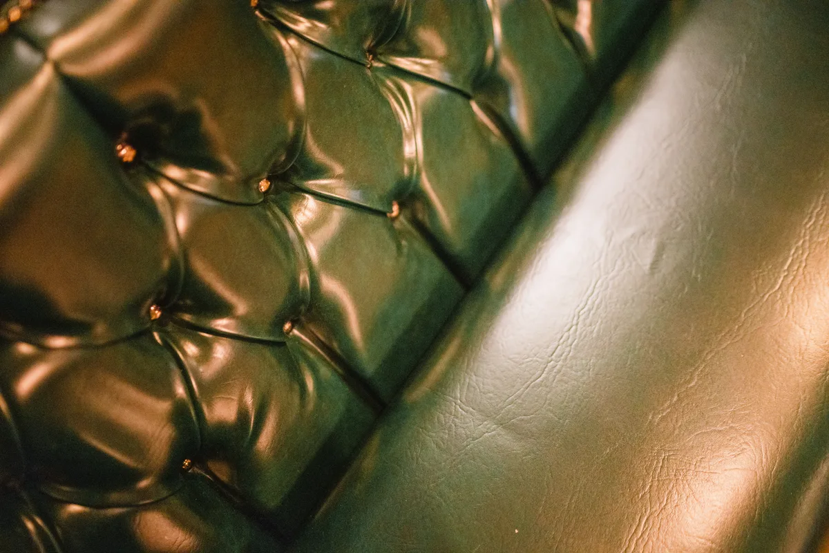 Emerald green pincushion leather banquette seating and timber wainscoting at The Anchor Digbeth