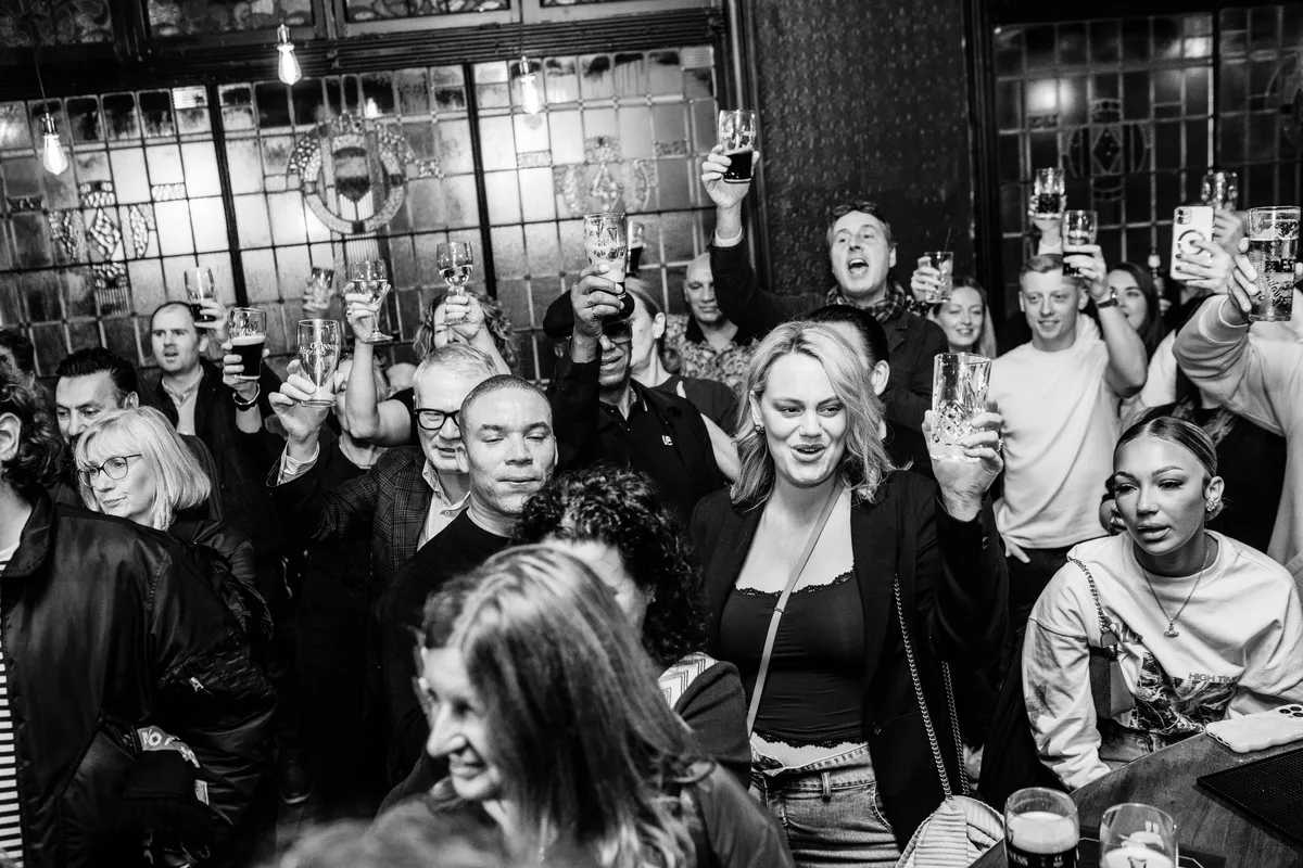 Packed crowd raising glasses of Guinness and ale at The Anchor Digbeth relaunch party